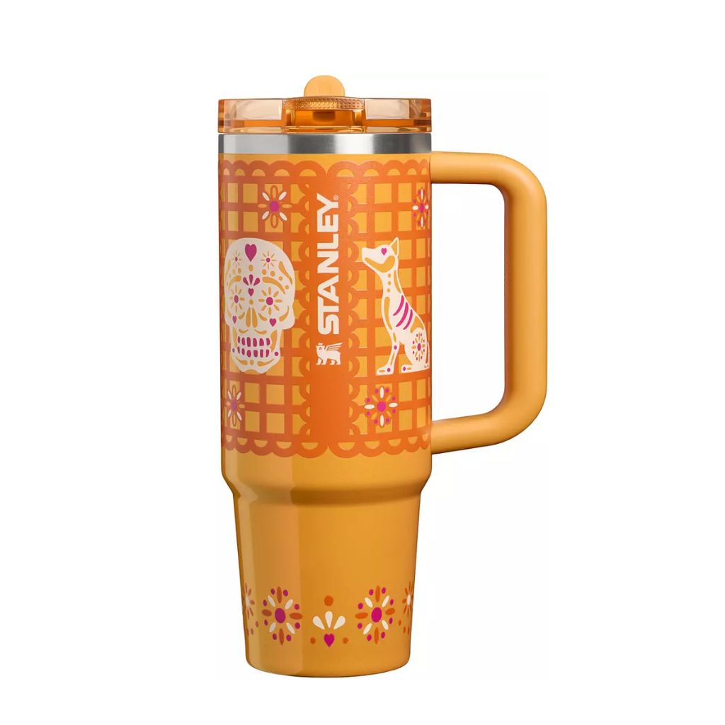 Stanley Marigold Papel Picado tumbler featuring golden-orange finish, terracotta cut-paper-inspired borders, colorful sugar skull, decorative dog illustration, pink and magenta floral motifs, matching orange handle
