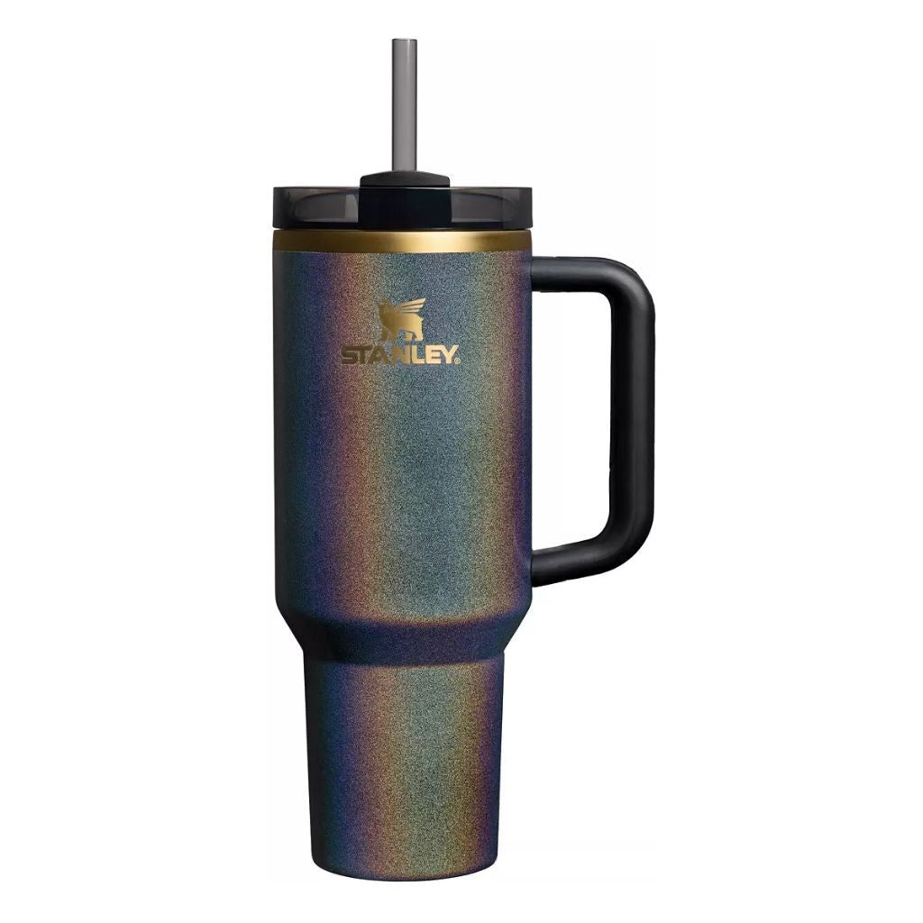 Stanley Fairy Dust tumbler featuring iridescent metallic finish with shimmering violet, midnight blue, teal, bronze, and gold tones, black handle, smoky black lid, charcoal straw, gold-tone rim, and metallic gold Stanley logo.